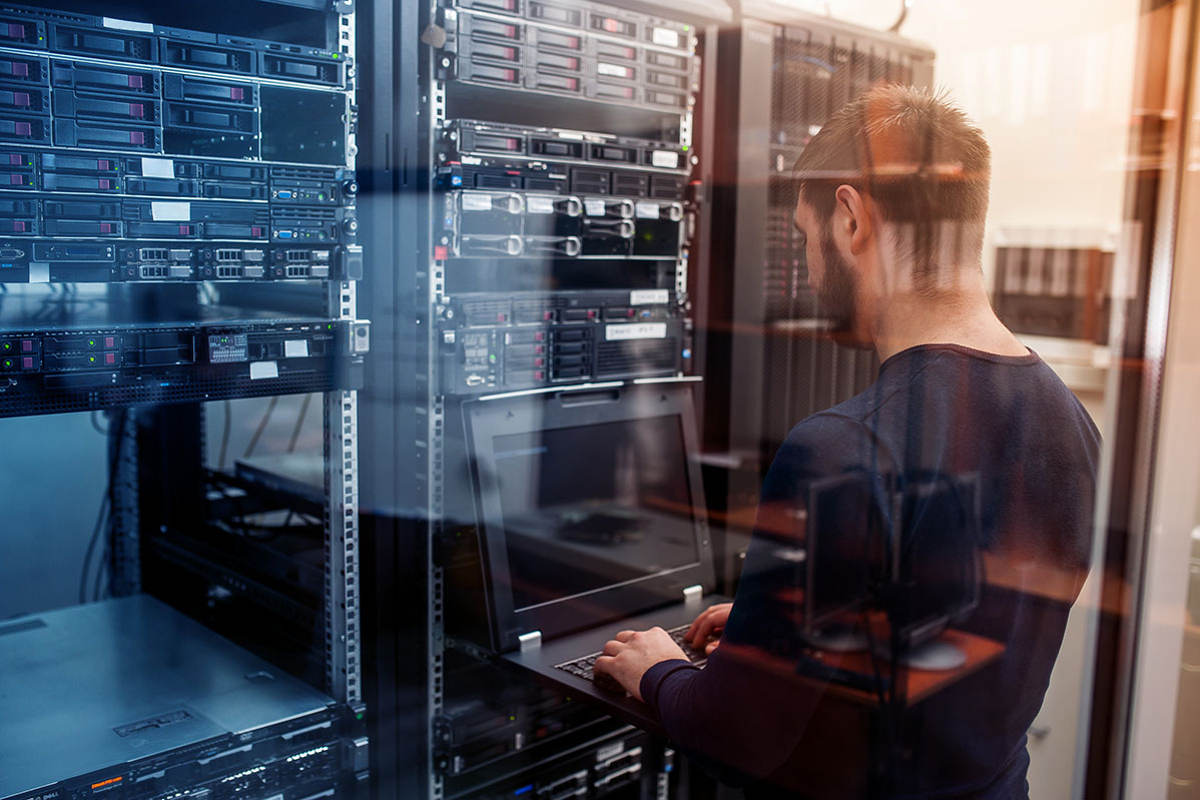 Man looking at multiple servers and computer machines