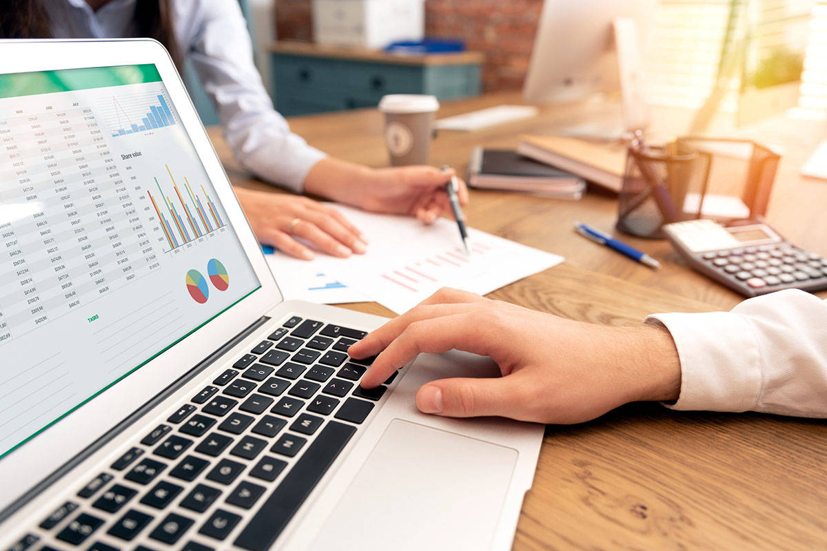 Man using laptop with numbers and graphs on the screen