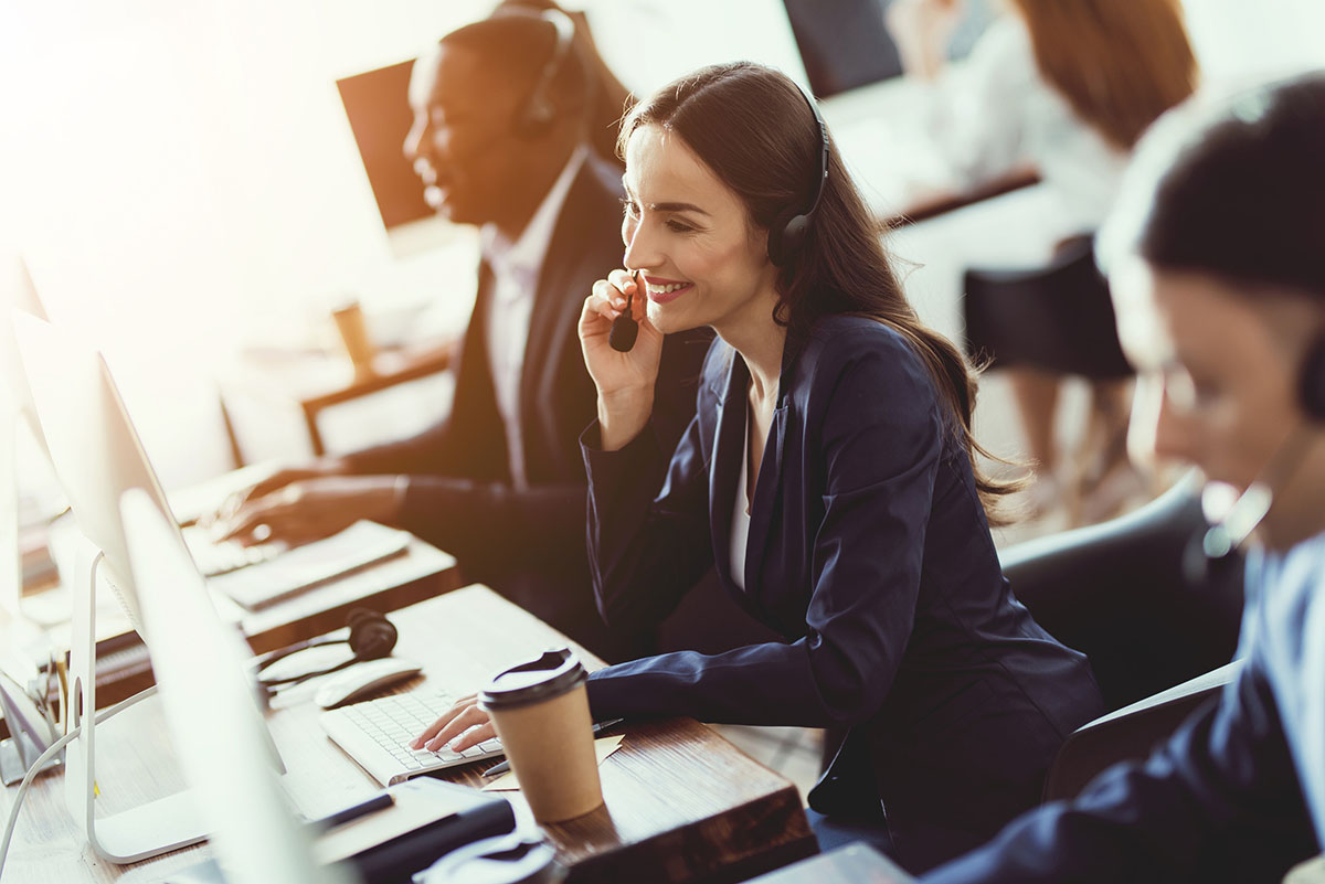 Woman in office talking on headset while sitting at a computer